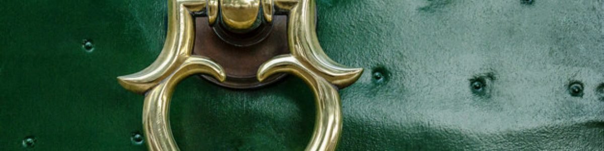 Beautiful metal handle on a green front door. Close-up.